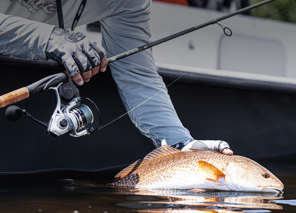Person holding an Eagle fishing rod with a fish caught on a boat.