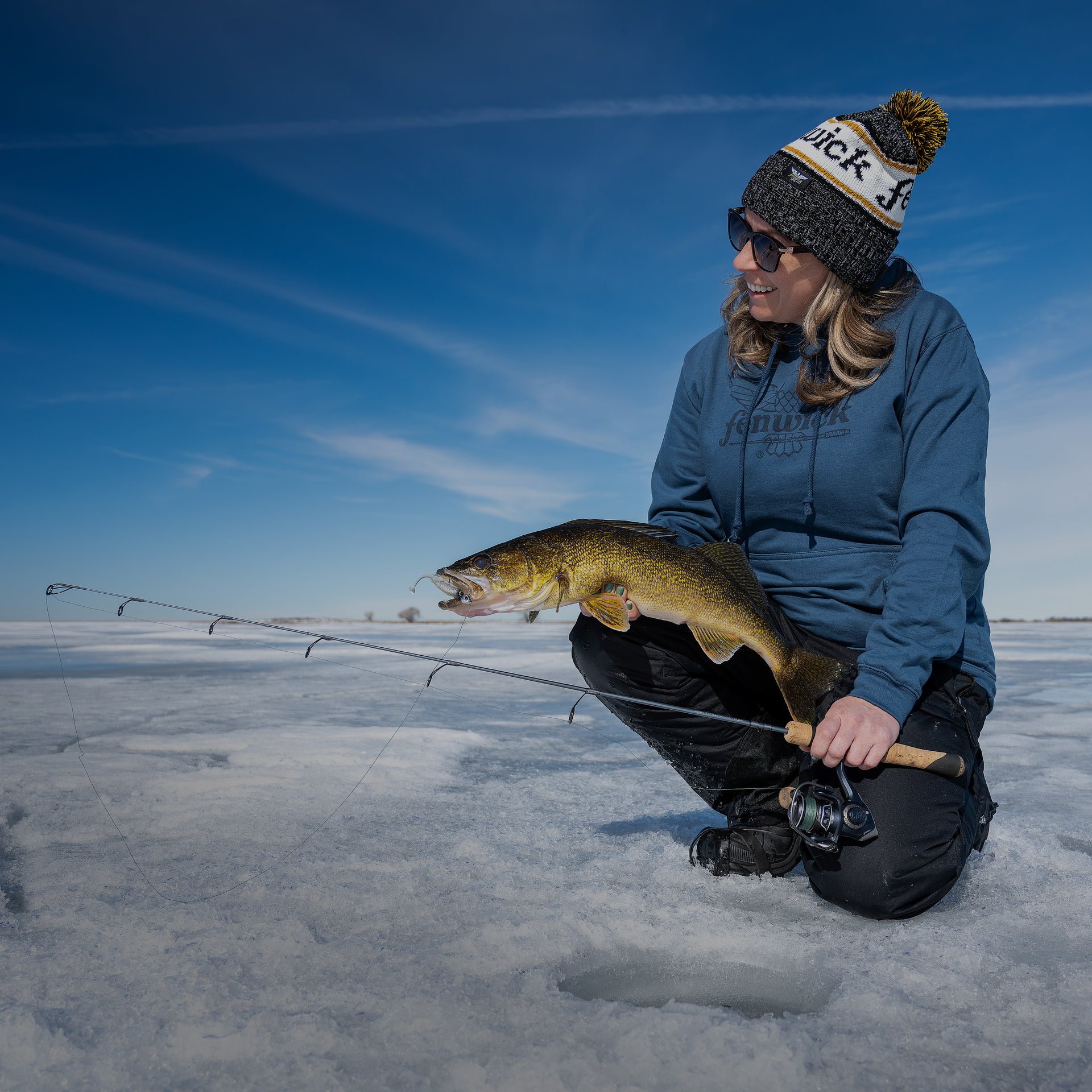 Person on a frozen lake holding a fish caught from ice fishing