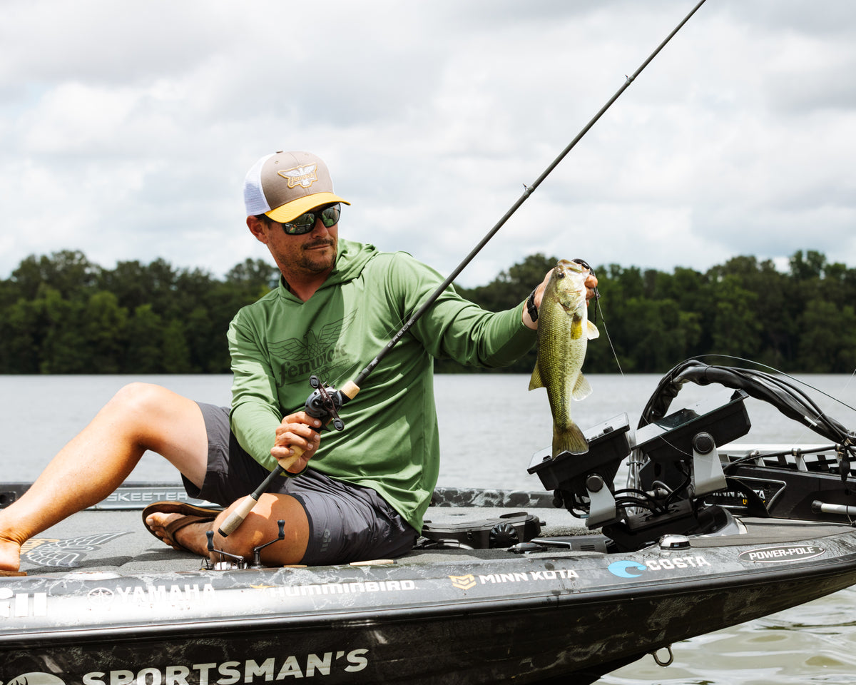 Man holding a caught fish wearing a Fenwick sunshirt