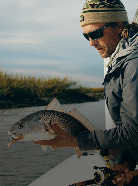 man fishing inshore holding a fish